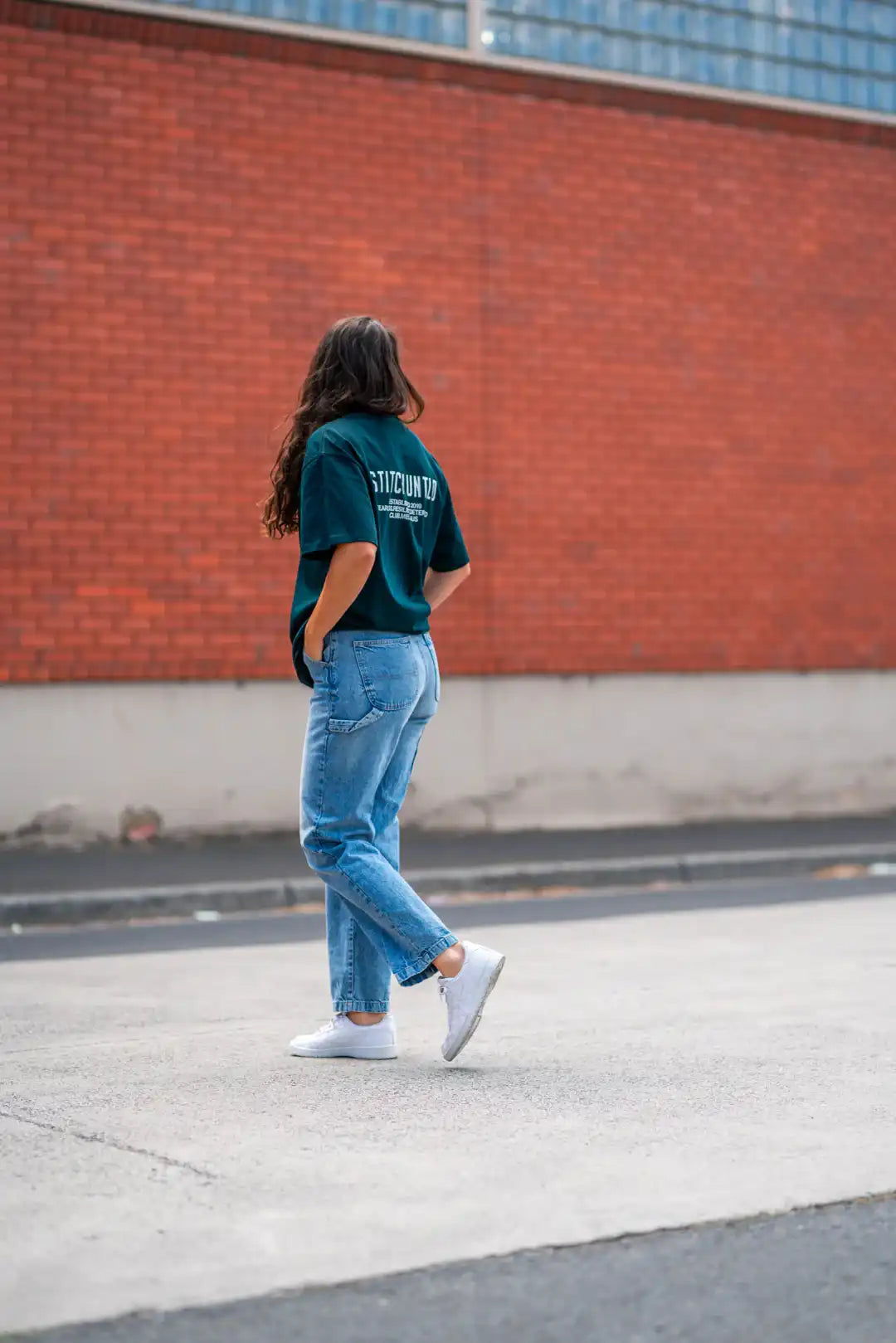 Person crossing Melbourne street wearing green stitch untitled club tee